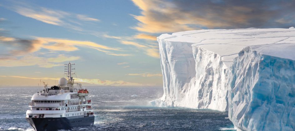 Kreuzfahrtschiff an einem riesigen Eisberg.