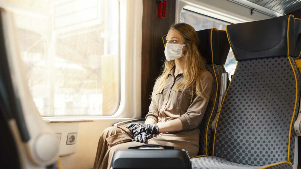 Frau mit Maske im Zugabteil